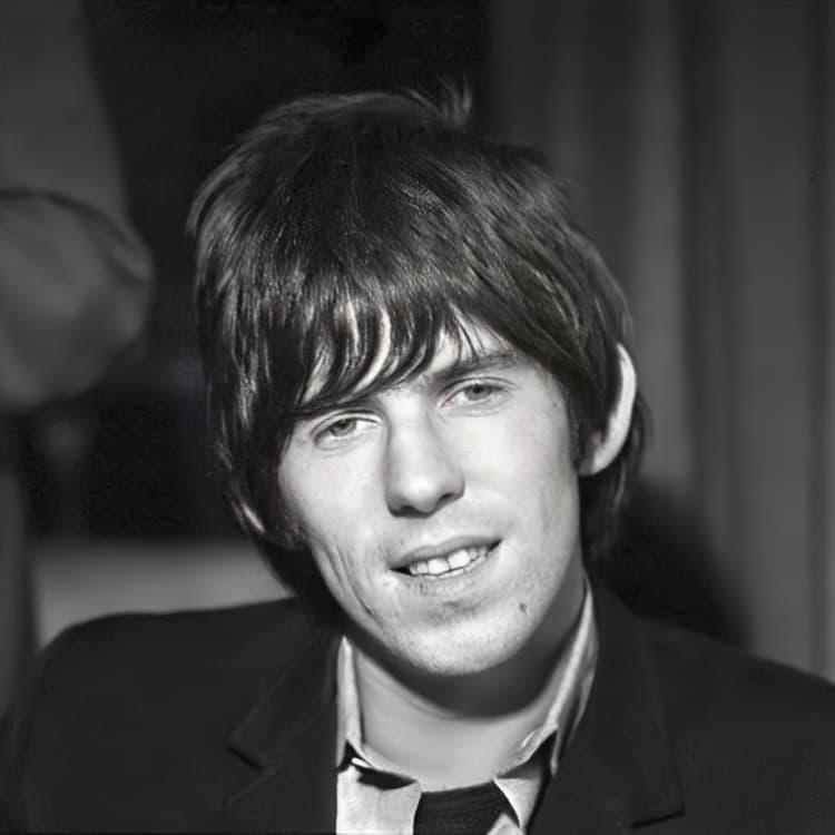 Keith Richards in 1965, smiling, in a dark jacket and tie