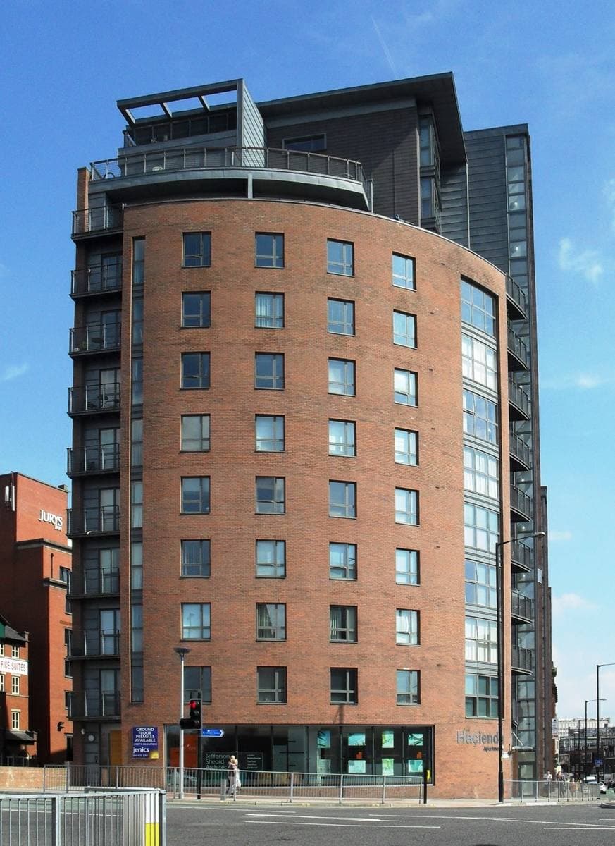 A curved brick apartment block on a corner under blue sky