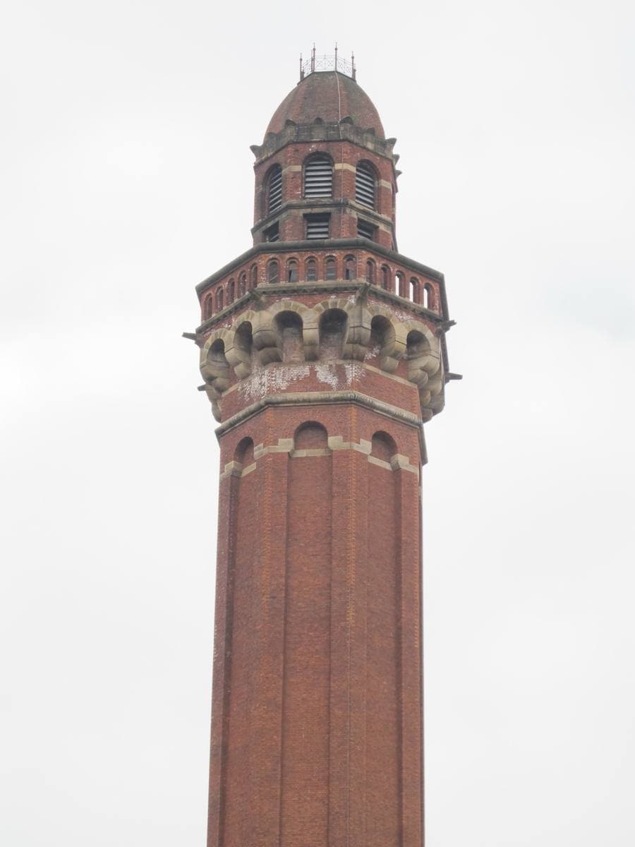 A tall brick tower with a crenellated top against a pale sky