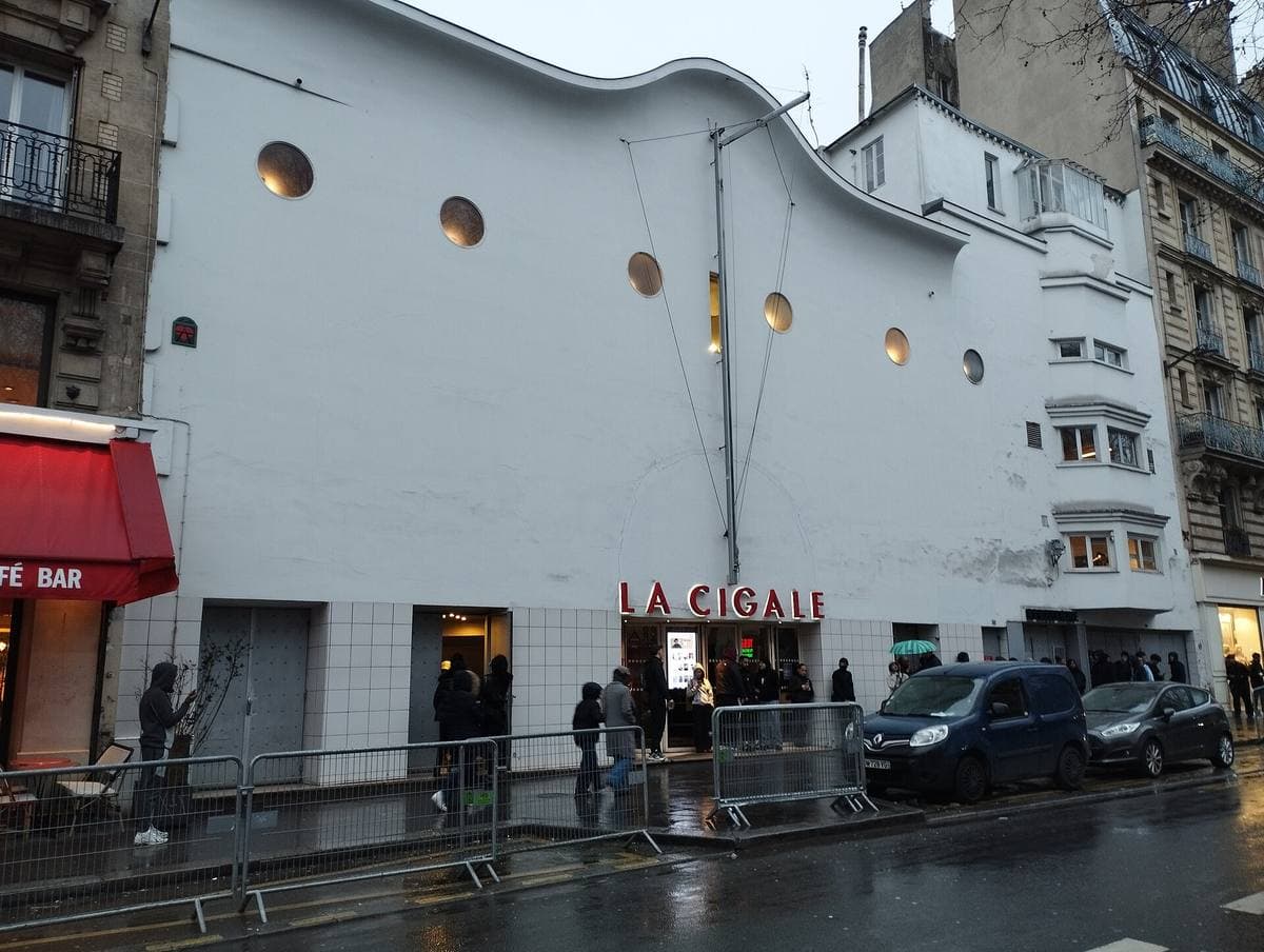A wavy white music-hall front with round porthole windows and red La Cigale lettering above the doors