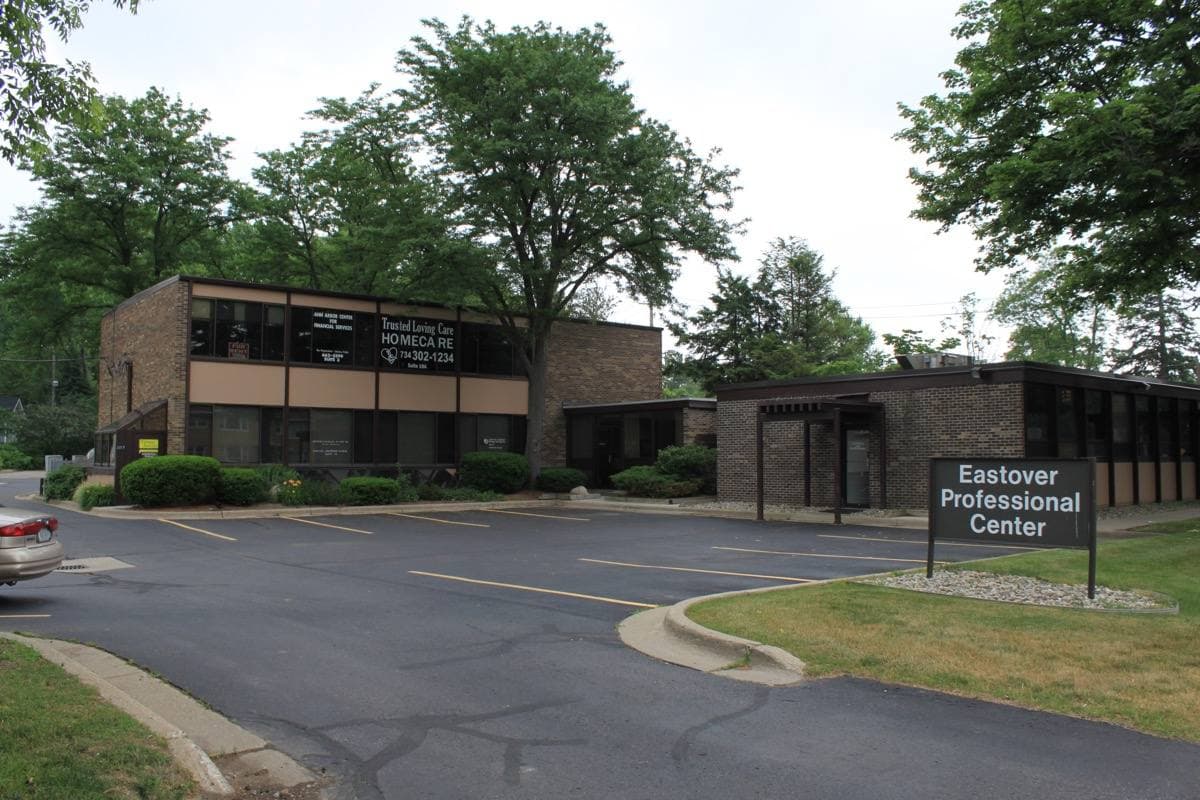 A low building beside a tree-lined suburban road in summer