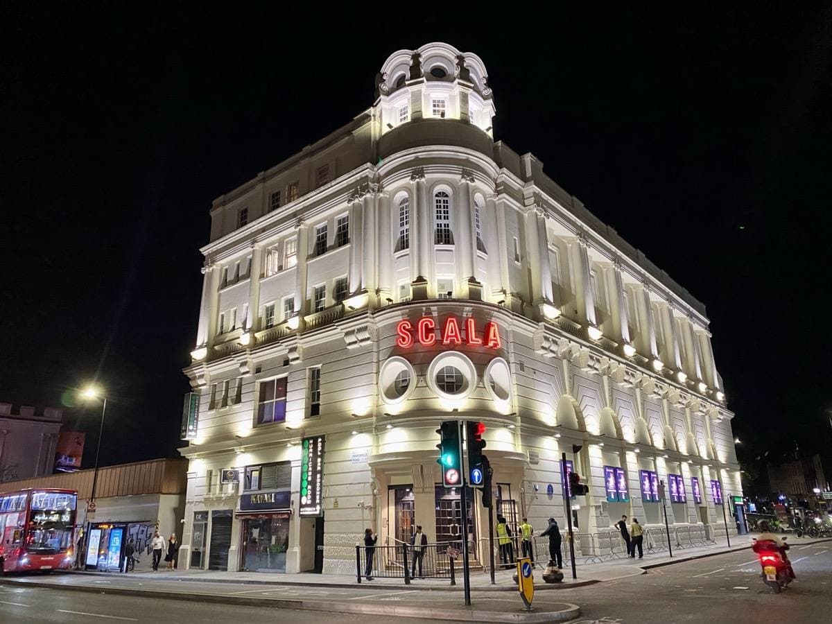A curved cinema building on a corner at night