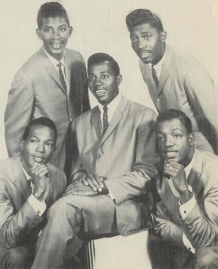 Five young men in light suits and ties posed together