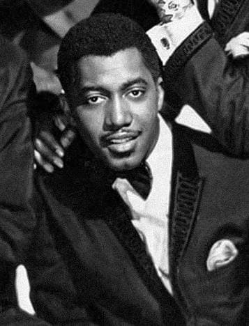 Otis Williams in a tuxedo, chin resting near his hand, 1964