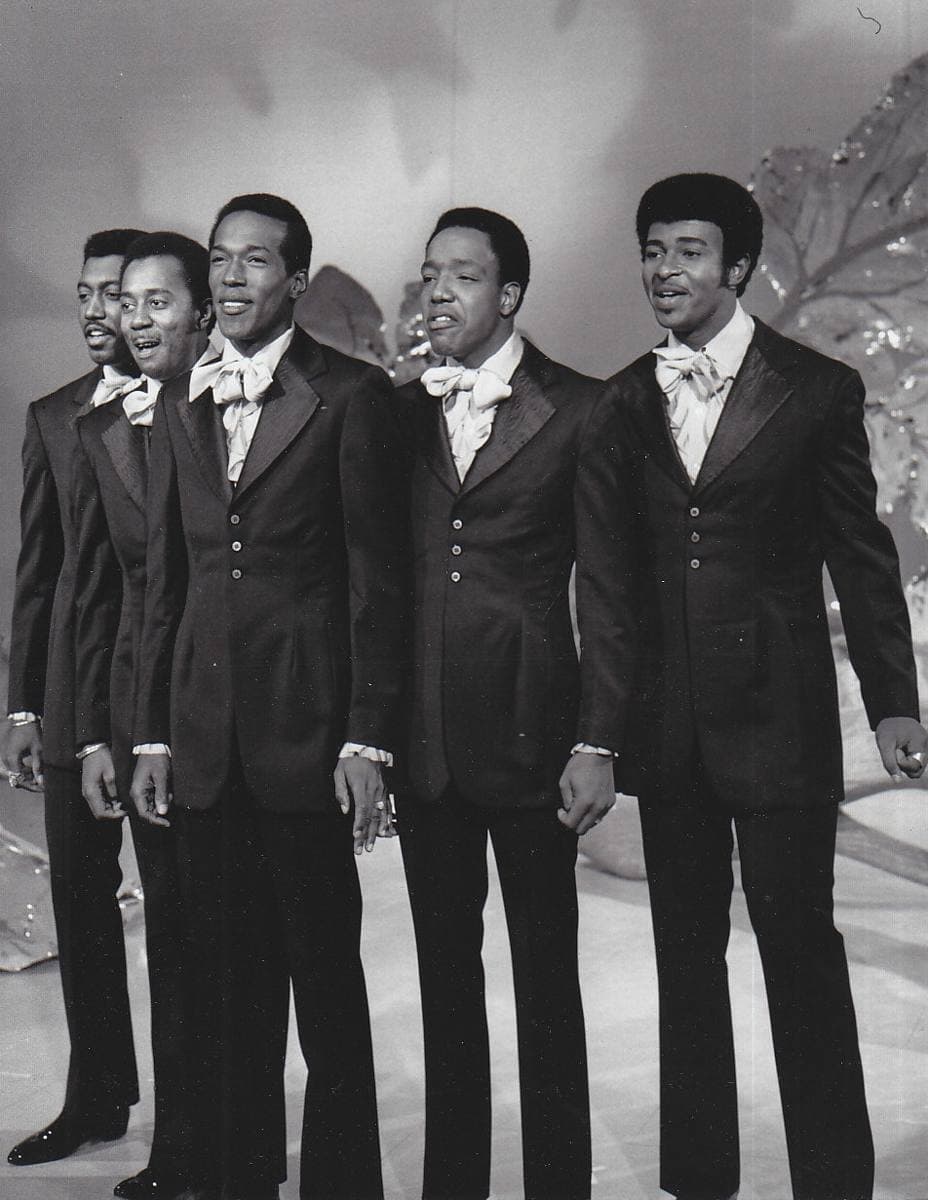 Five Temptations in dark suits and pale bow ties singing on a television stage