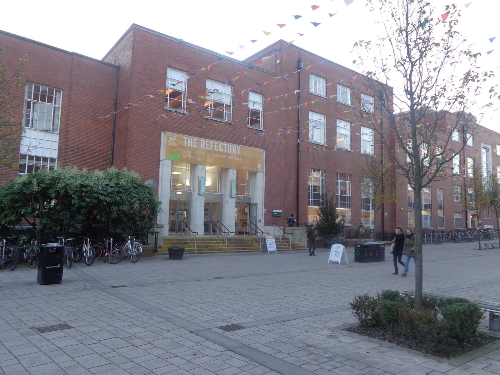 A red-brick university building with a glass entrance on a paved square