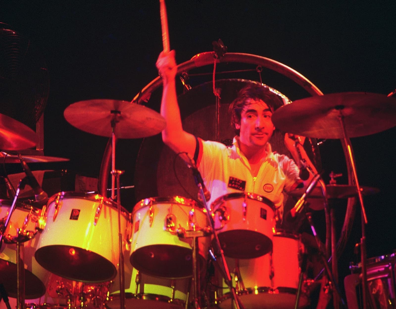 Keith Moon behind a white drum kit, one stick raised high