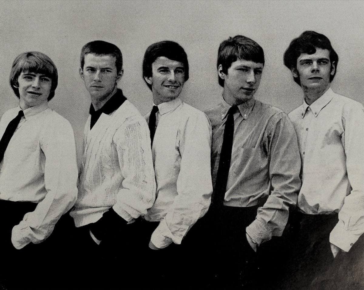 Five young men in shirts and ties standing in a row, black and white