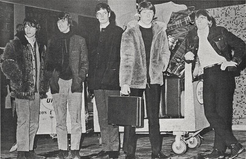 Young men in coats walking off an aircraft, black and white