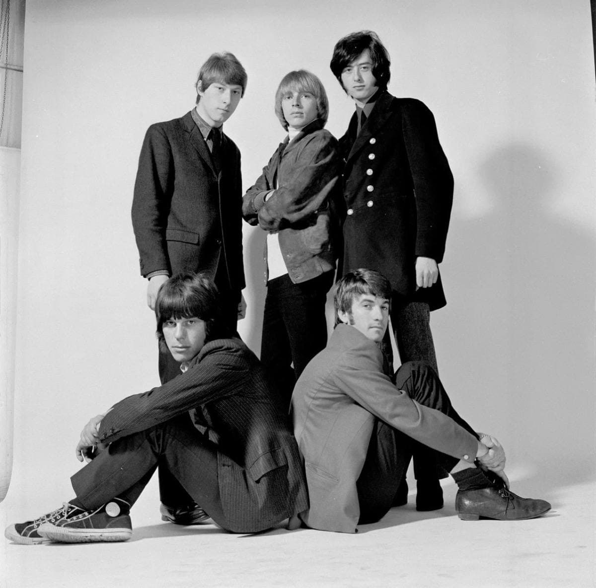 A group of young men with guitars posing together, black and white