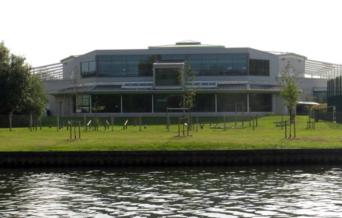 A modern leisure centre beside a river with trees