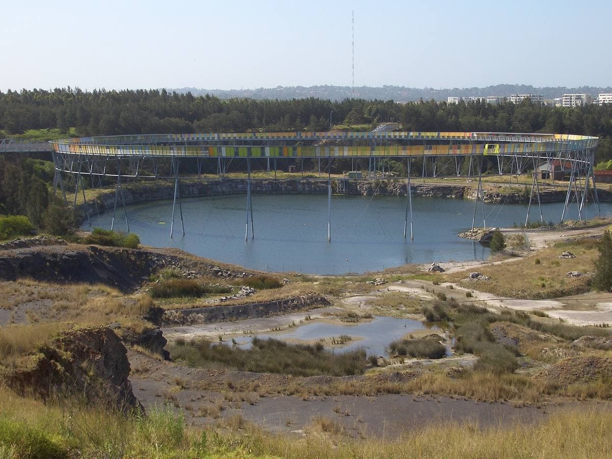 A flooded quarry pit with a circular walkway on stilts around its rim