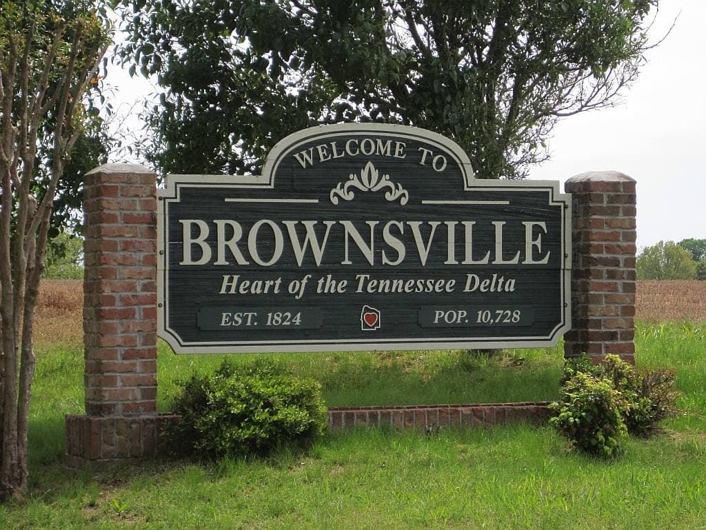 A brick Welcome to Brownsville sign in a planted bed