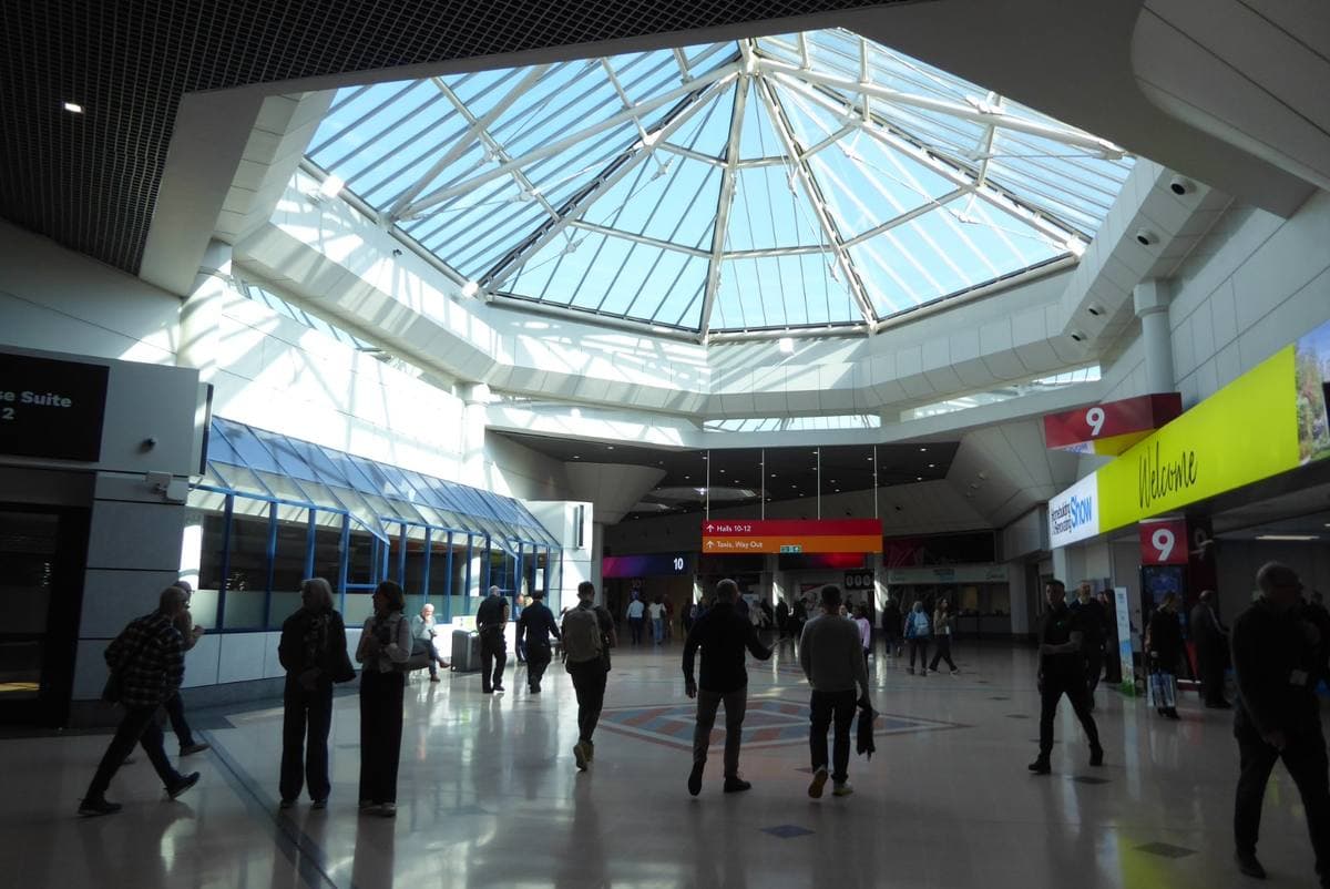 A bright atrium under a glass roof with signs to the halls