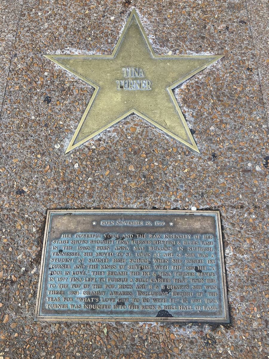 A brass star set into a pavement with a bronze plaque below it