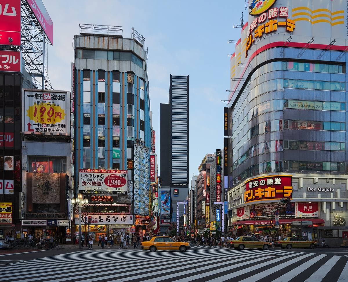 A wide zebra crossing in Kabukicho under tall buildings covered in signs