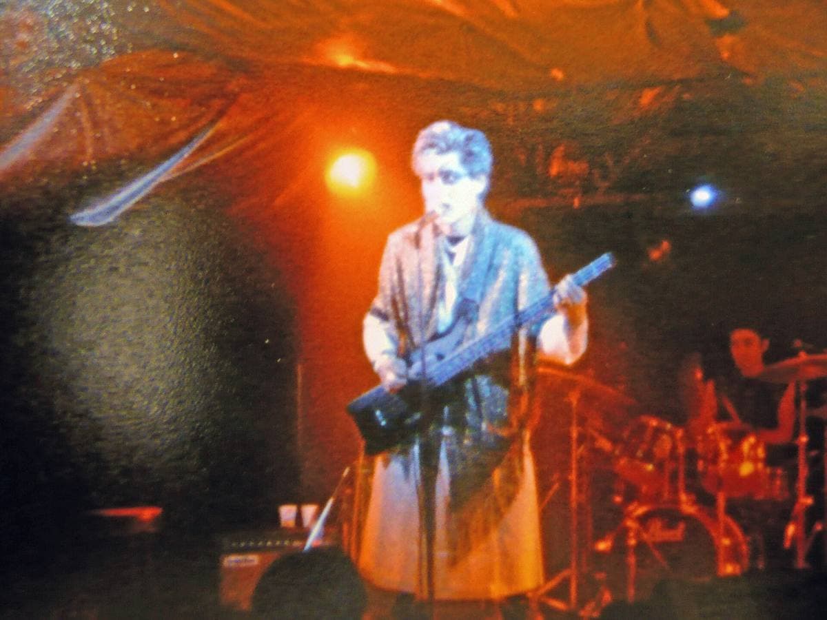 A singer with a guitar under orange stage light on a small club stage