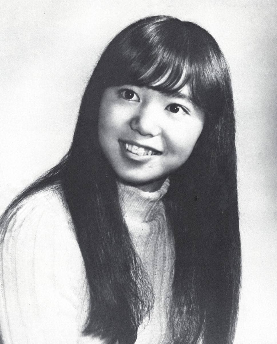 Black-and-white portrait of a smiling teenage Mariya Takeuchi with long straight hair and a ribbed jumper