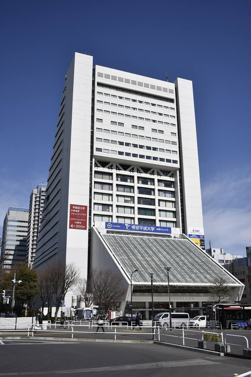 A tall white triangular building with a sloping glass base under blue sky