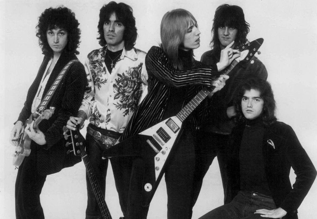 Five young men with long hair and guitars posing against a white background, black and white