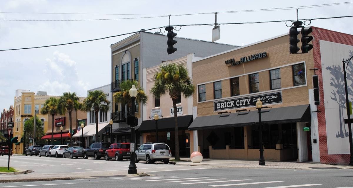 Two-storey brick shopfronts and palm trees on a corner in downtown Ocala