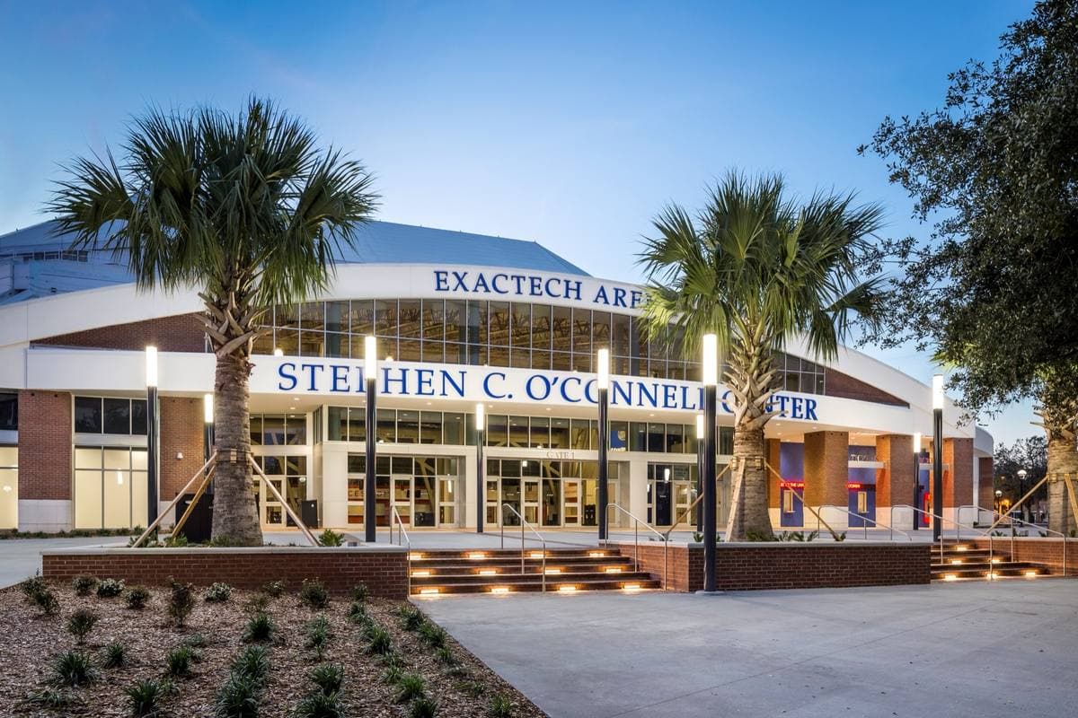A modern arena entrance with palm trees and the O’Connell Center name over the doors
