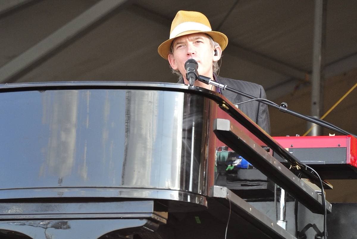 Benmont Tench in a straw hat at a grand piano on an outdoor stage