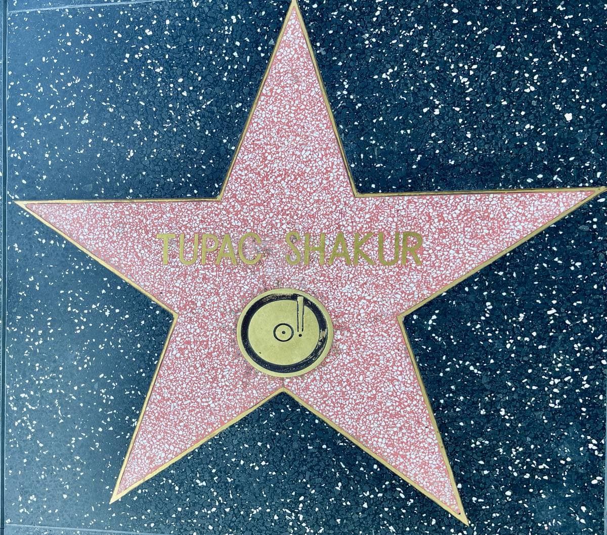 A pink terrazzo star with a brass record emblem, engraved Tupac Shakur