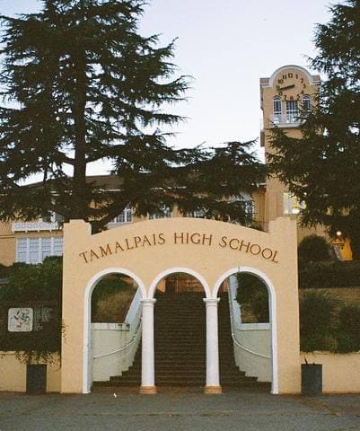 A pale Spanish-style arch and clock tower at dusk