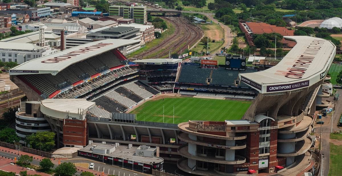 An aerial view of a rugby stadium with a green pitch and stands on three sides