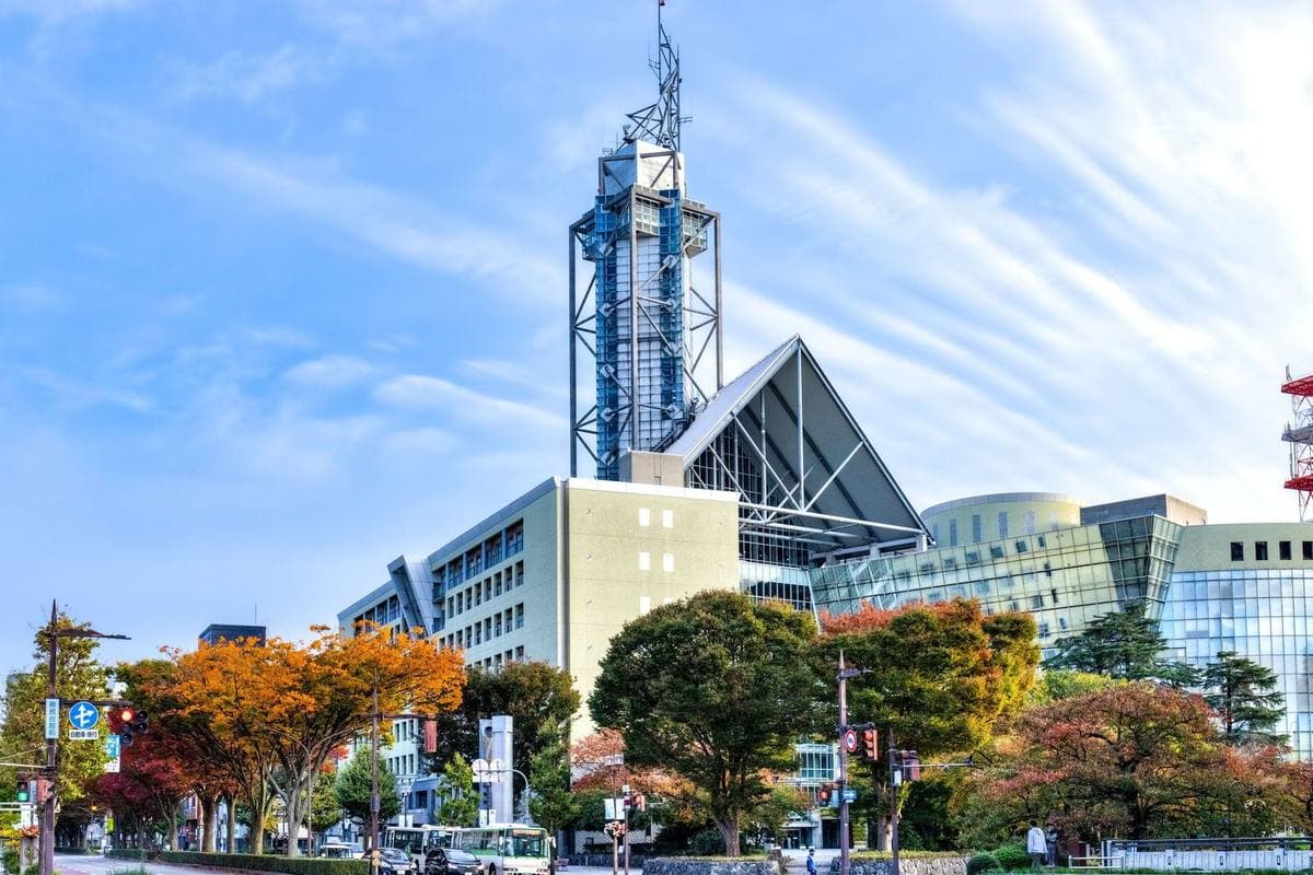 Toyama City Hall’s tower behind autumn trees on a wide avenue