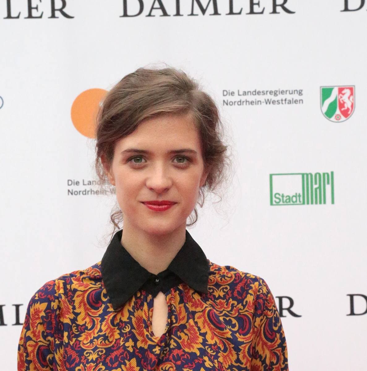 Liv Lisa Fries with her hair pinned up, in a patterned blouse with a black collar