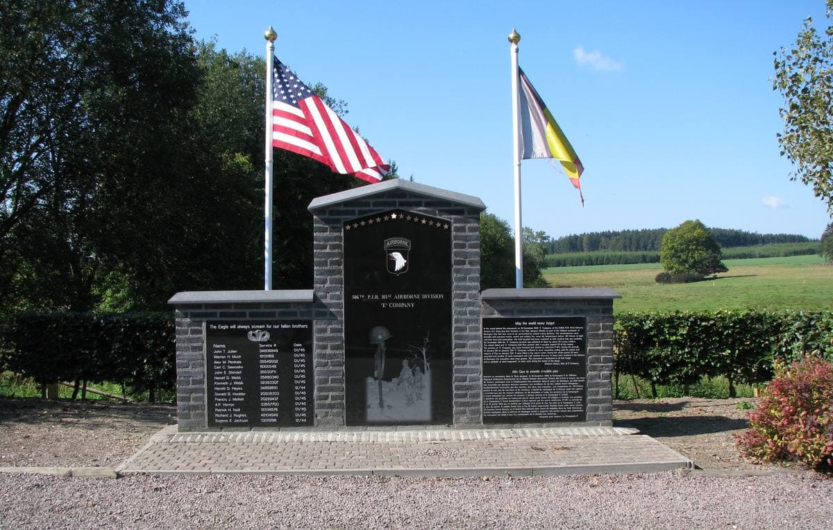 A stone monument with three plaques by a path