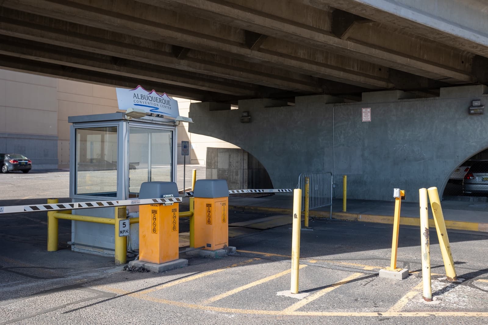A small parking booth with a barrier arm under a concrete overpass