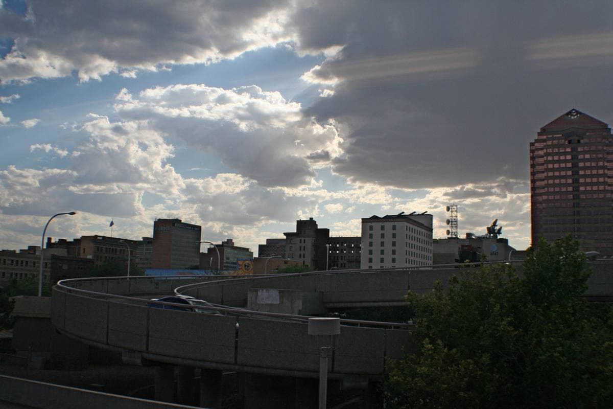 The low towers of downtown Albuquerque under a big late-summer sky, seen from a train