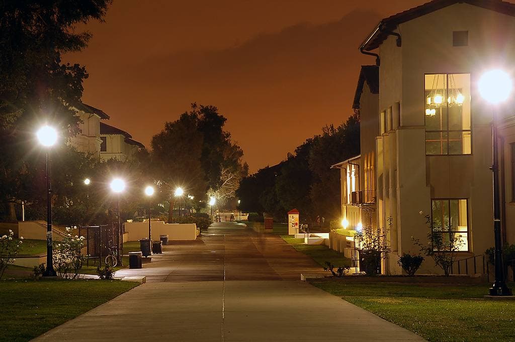 Lawn quad framed by Mediterranean-style college buildings with red tile roofs