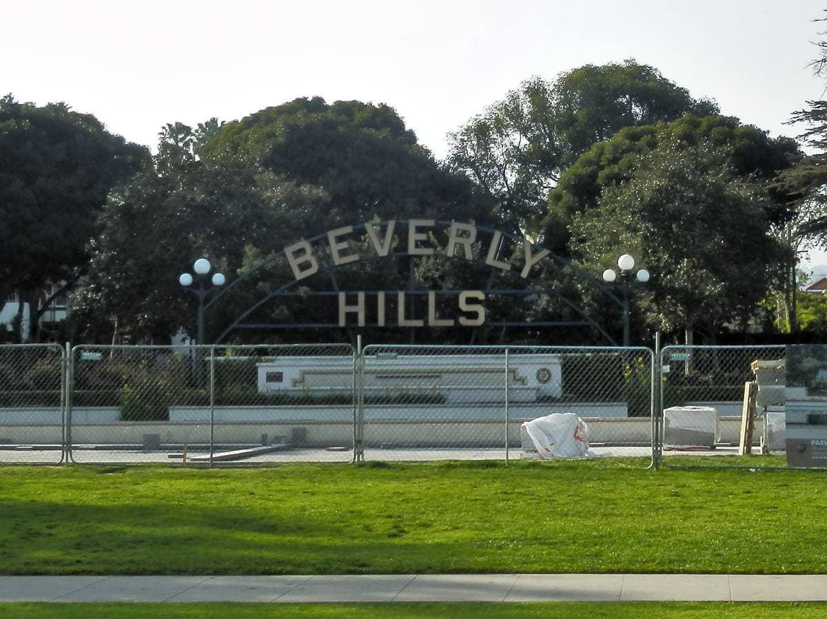 Long white Beverly Hills lettering on a low wall beside a lily pond and lawns