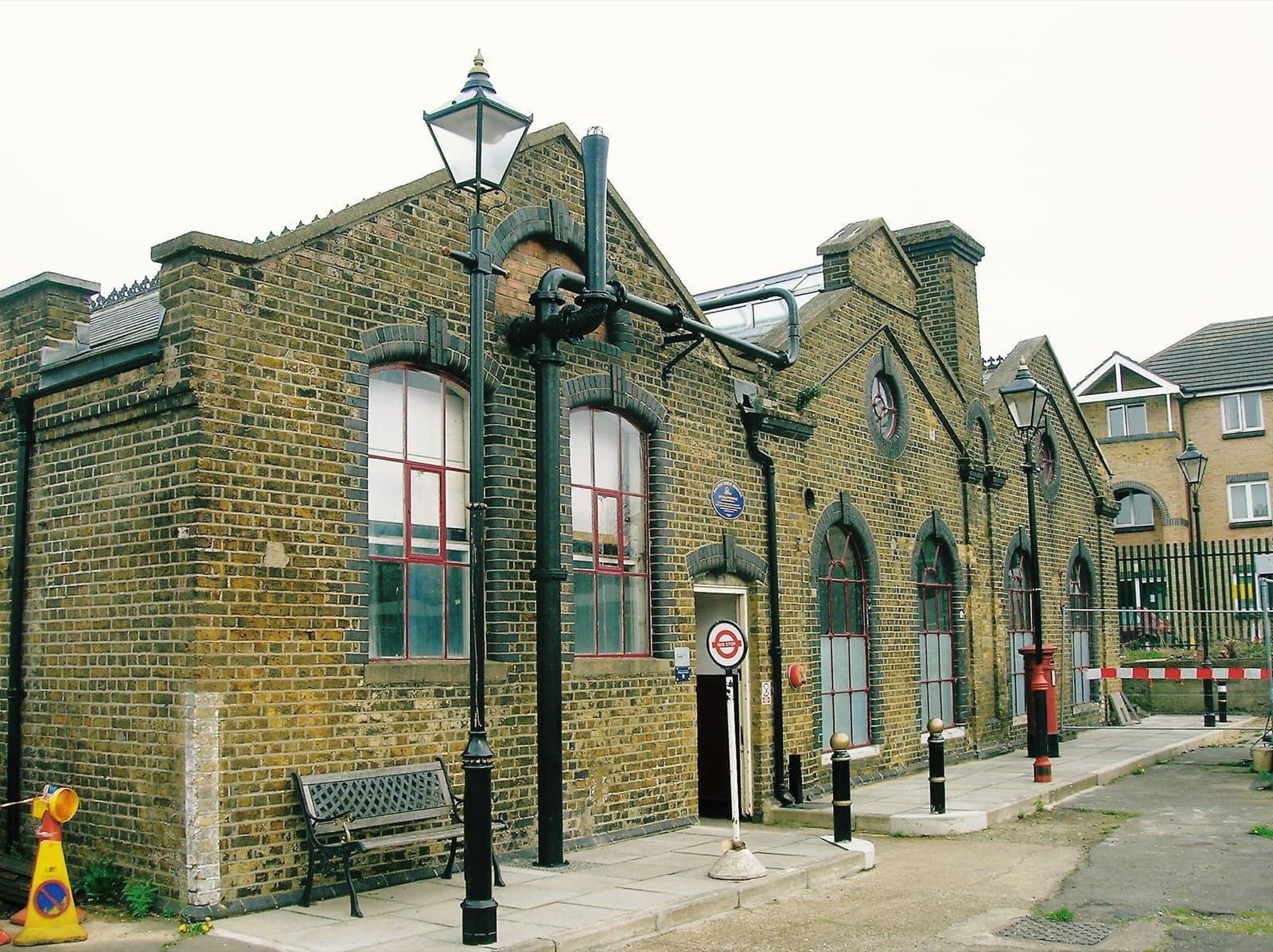 A Victorian brick pumphouse with tall arched windows and a lamp post