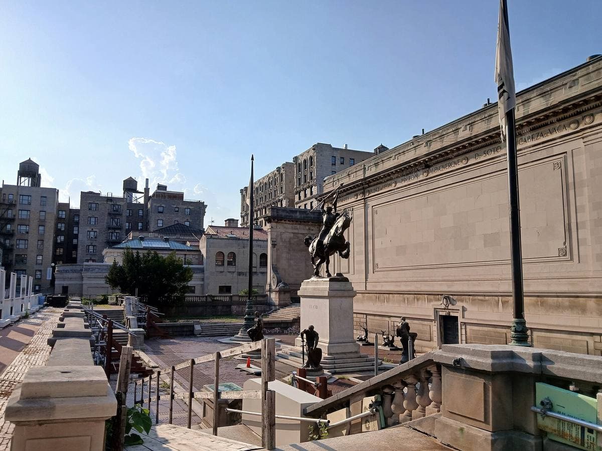 A stone plaza between classical buildings, an equestrian statue at its centre