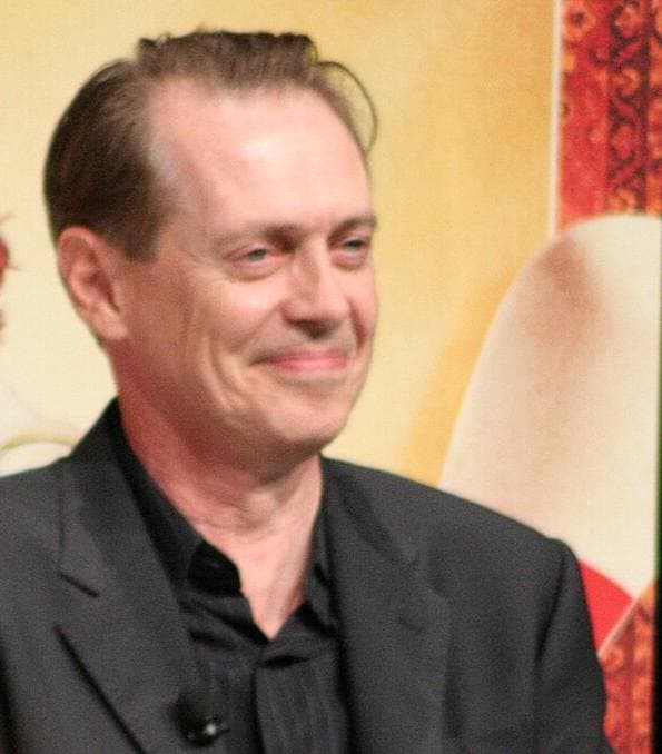 Steve Buscemi smiling, in a dark jacket and shirt