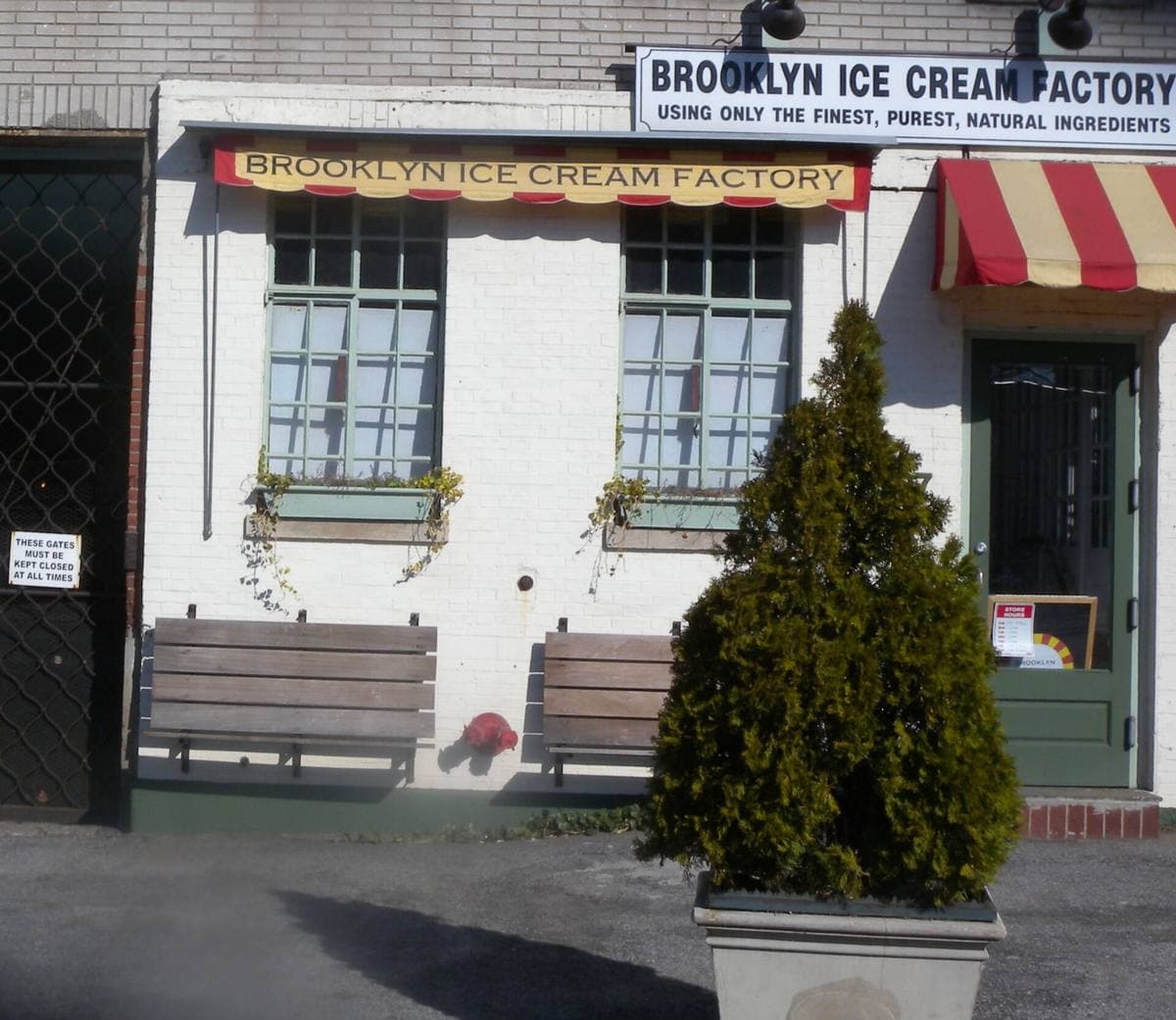 A small white brick building with green windows and a striped awning on Commercial Street
