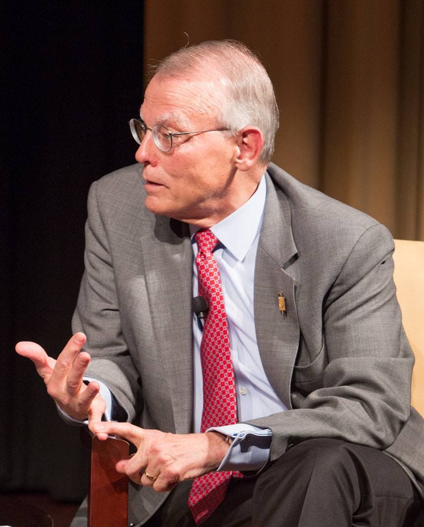 Nelson Johnson in a grey suit and red tie, speaking from an armchair