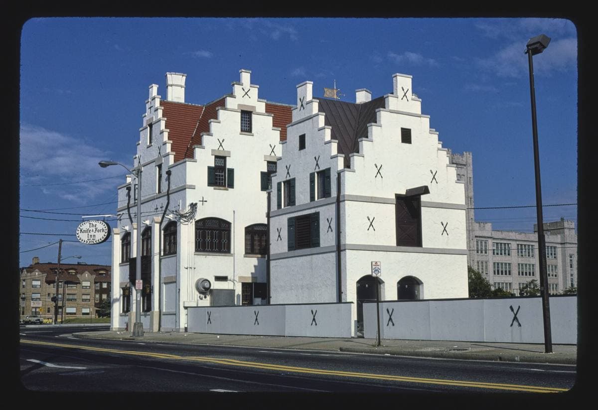 A white building with stepped Flemish gables against a blue sky