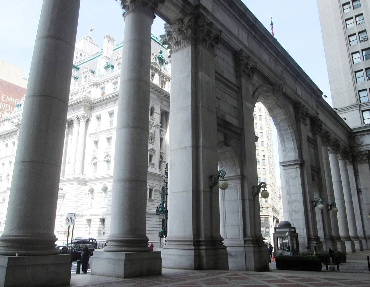 Tall stone columns of a colonnade, with a coffered arch