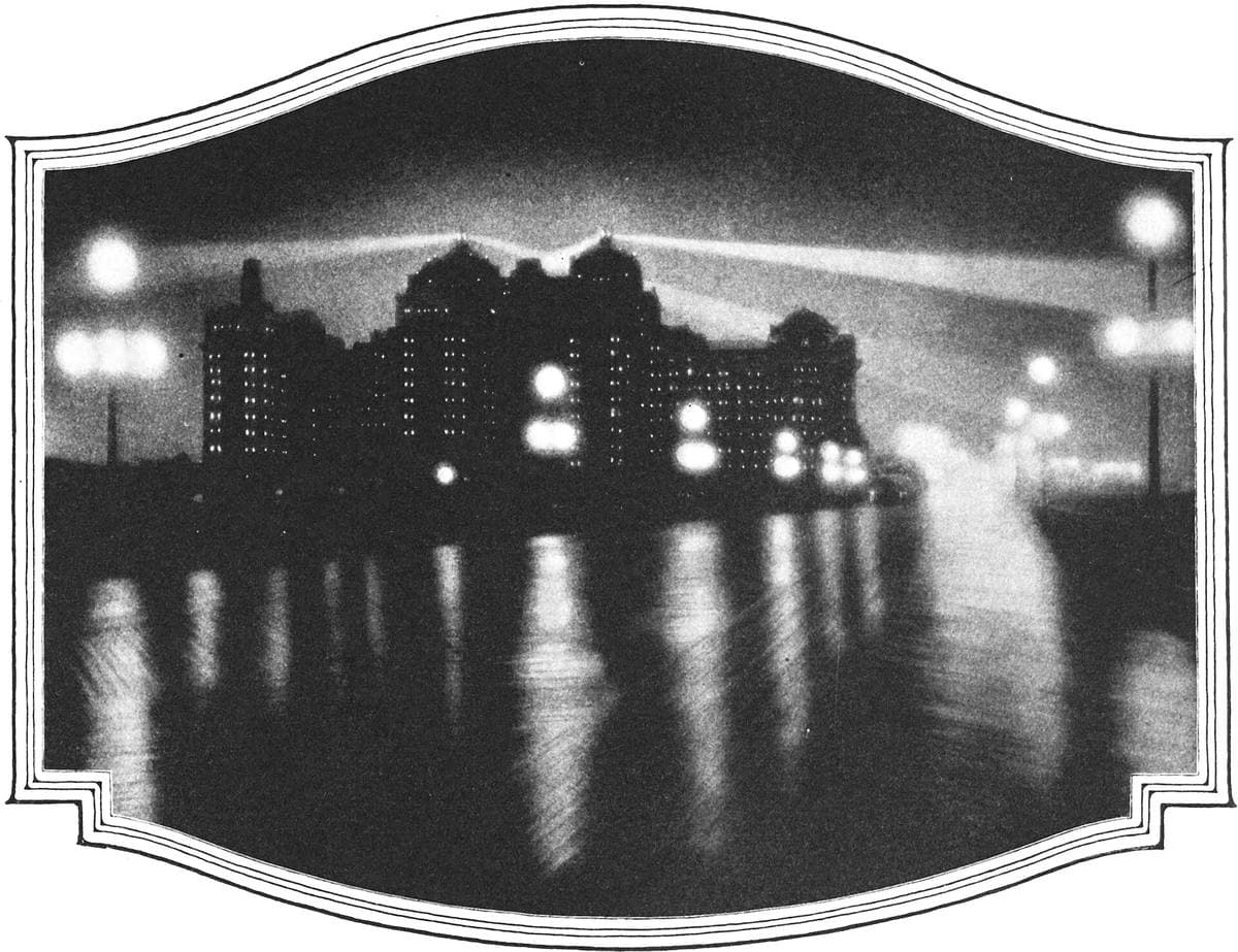 Night on a wet boardwalk, lamps reflected in the boards, tall hotels behind
