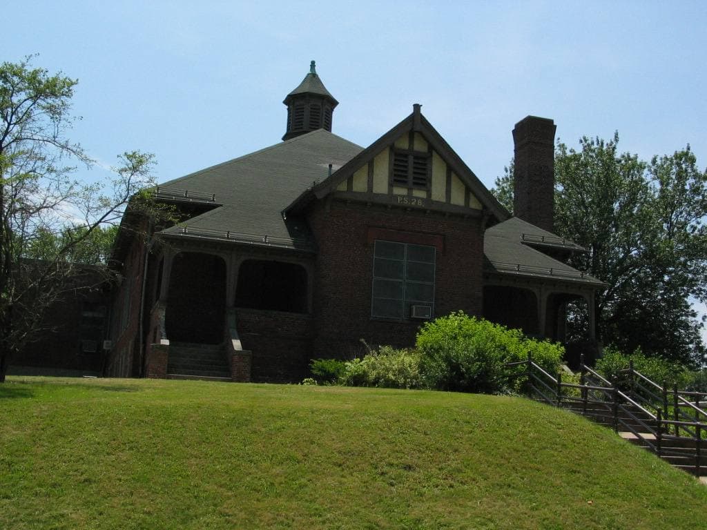 A brick and timber village building on a grassy bank