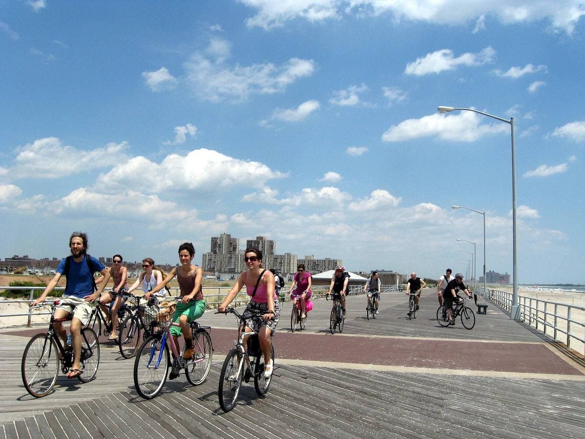 Cyclists on a wide boardwalk under a blue sky