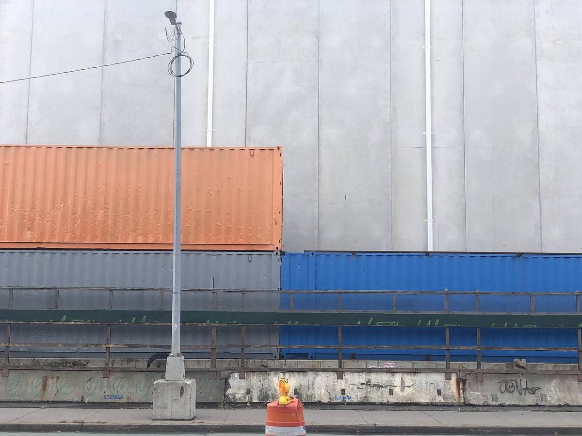 Orange and blue shipping containers stacked against a grey stage wall