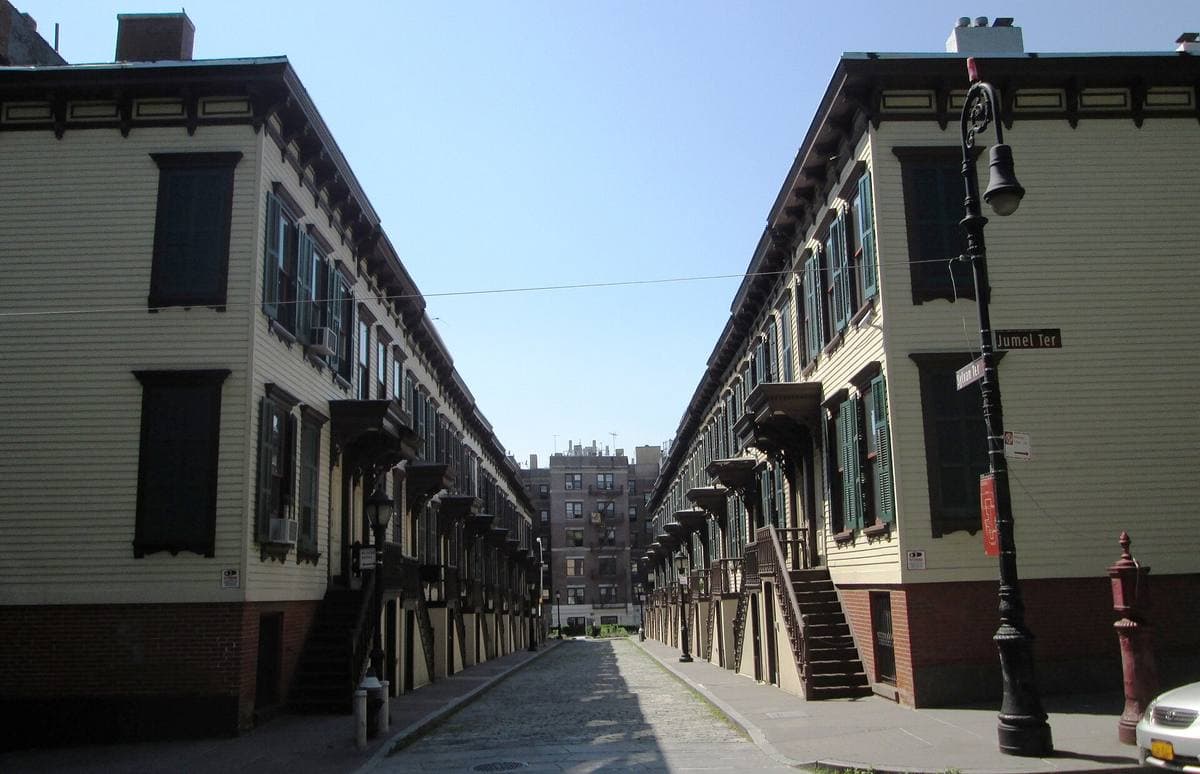 A narrow cobbled street between two rows of painted wooden houses