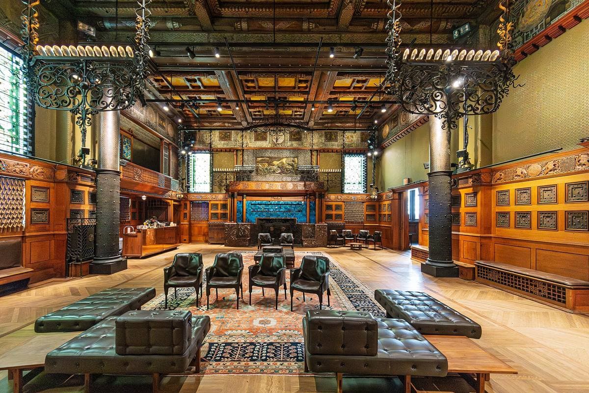 A dark panelled room with carved wood, lamps and leather seats